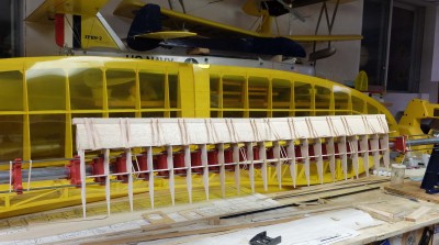 The leading edge wing sheeting is glued in place top and bottom. You can see the yet to be shaped leading edge being held in place with popsicle sticks and #64 rubber bands while the glue drys. Being a simple wing without ailerons I can usually complete everything with the exception of the bottom center sheeting and bottom side wing tip braces in while in the jig.