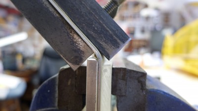 I used a couple of short lengths on angle iron to keep the straight parts straight. A length of aluminum with a radius filed on on provided the form. Bend line on the gear is lined up with the top of the form block.